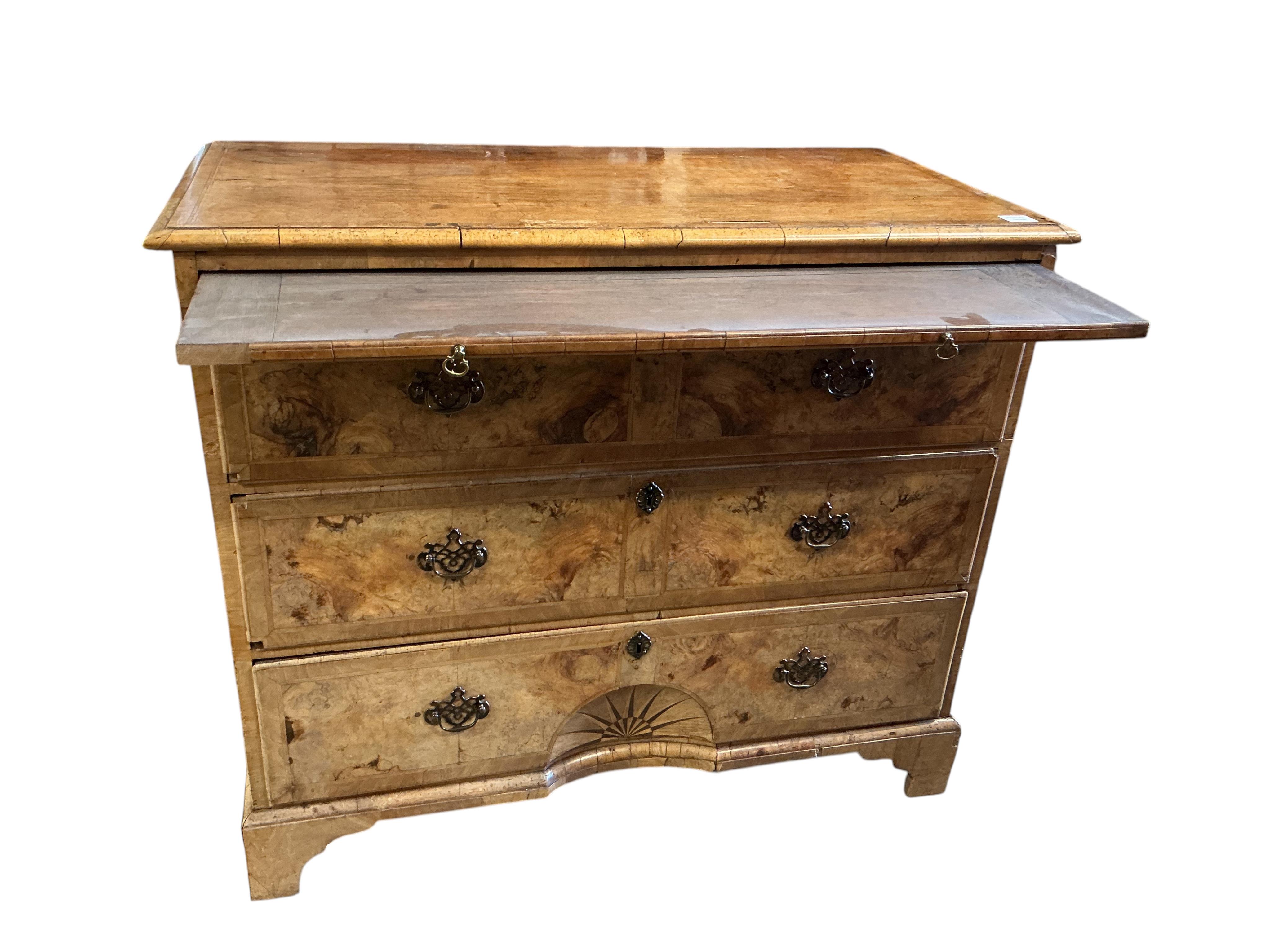 A mid 18th century feather banded walnut concave starburst walnut chest of three drawers, with brushing slide, width 108cm, depth 54cm, height 92cm